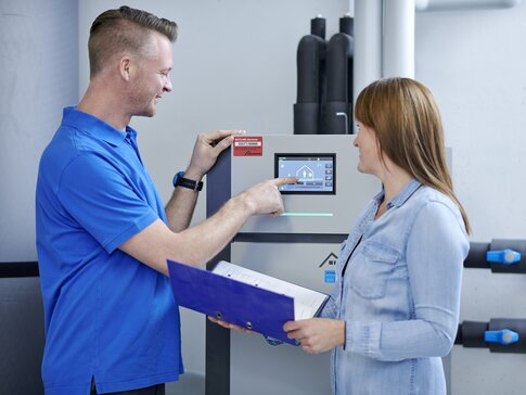 Techniker erklärt einer Kundin die Bedienung einer modernen bösch Heizungsanlage in einem Technikraum | © bösch heizung.klima.lüftung