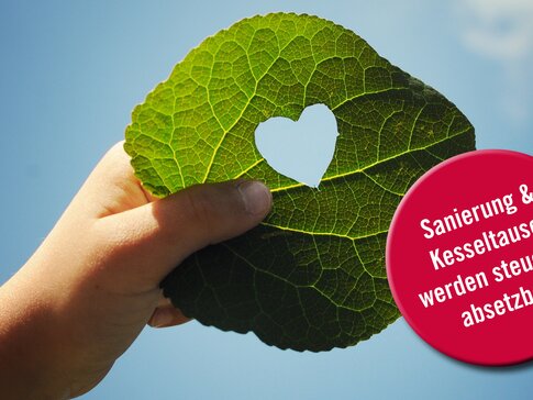 Hand hält Blatt in die Luft, welches ein Loch in der Mitte in Form eines Herzen hat | © bösch heizung.klima.lüftung