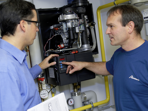 bösch Techniker steuert Heizsystem während jemand neben ihm steht | © bösch heizung.klima.lüftung