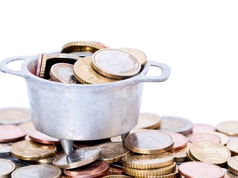 Euromünzen auf einem Haufen; auf dem Haufen ist ein Topf voll mit weiteren Euromünzen | © Frog 974 - stock.adobe.com